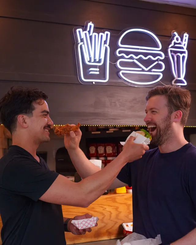 Ryan and Marty trading bites under the neon burger sign at Marty's