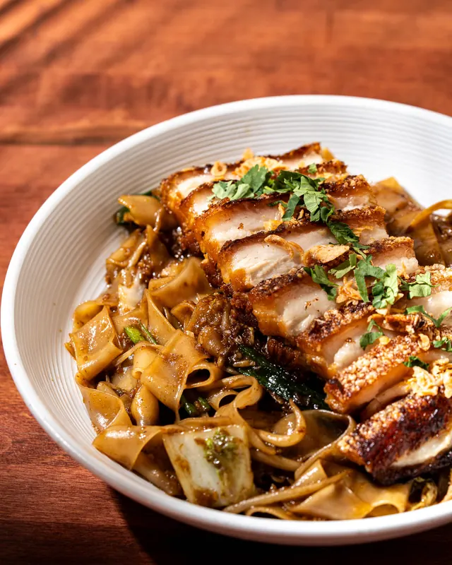 Crispy pork belly over stir-fried rice noodles