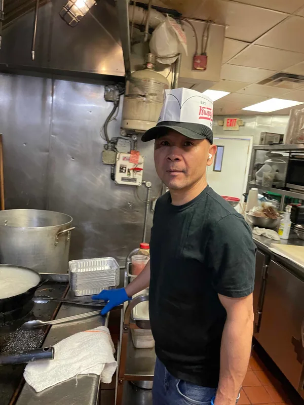 A cook in a cap standing by the stockpots